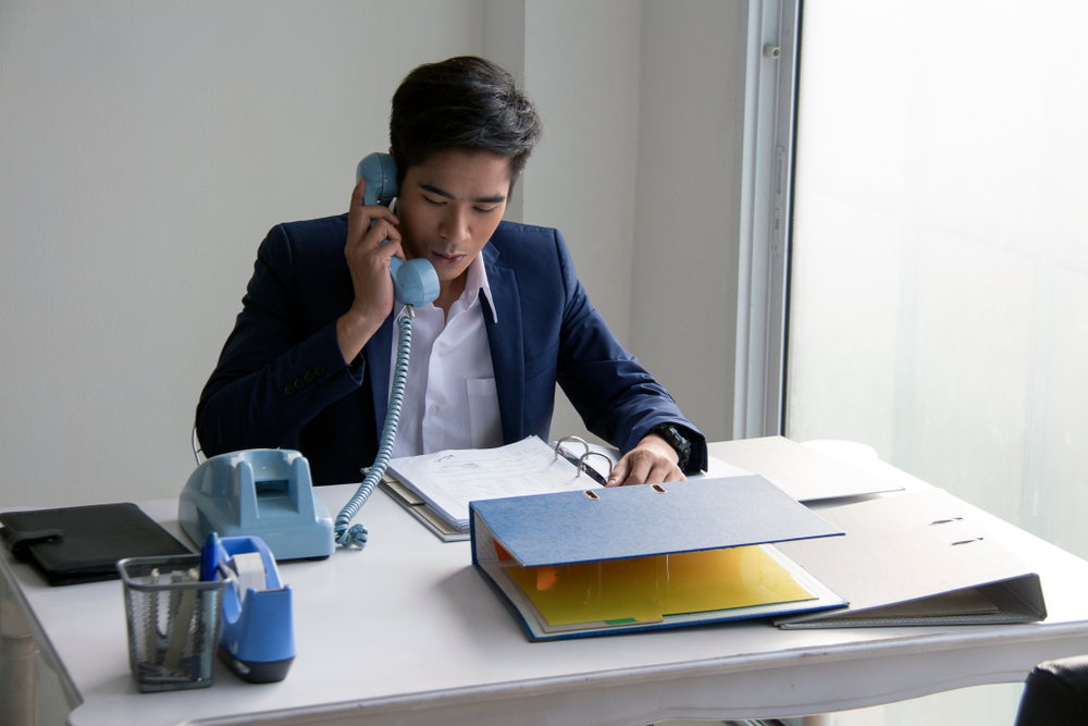 Business employees conducting marketing follow-up calls using telephone communication